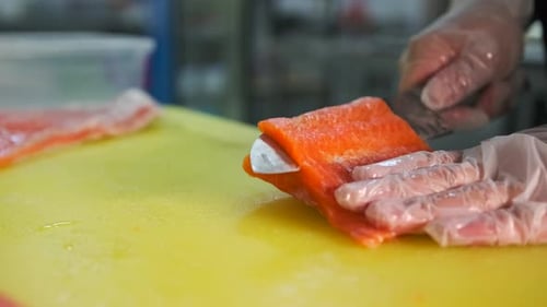 Chef preparing fresh salmon fillet, close up of kitchen yellow counter.
