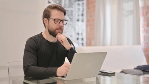 Man with Laptop Thinking in Bright Office