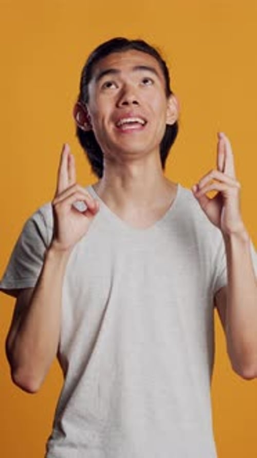 Young Adult with Fingers Crossed Gesture Smiling