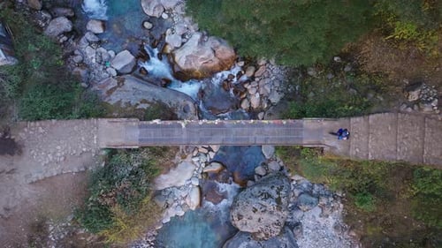 Lone Hiker Traversing Narrow Wooden Suspension Bridge Over a River in Monjo Revealing Rugged