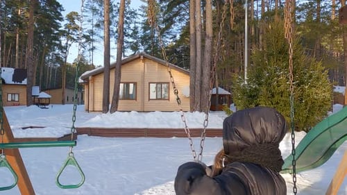 Teenage Girl Swinging in Snow Covered Park