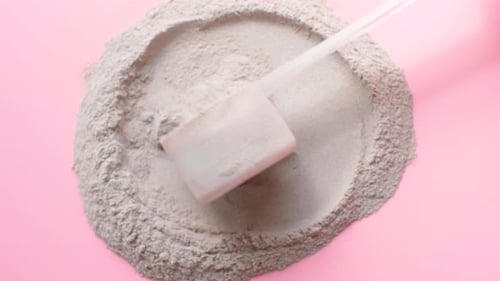 Gray Powder and Scoop on Pink Surface