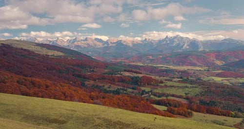 timelapse view of Snowy mountain peaks, orange and green forest in fall autumn season on a sunny and