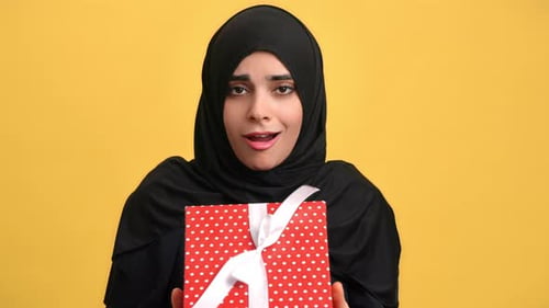 Portrait of Happy Amazed Arab Woman with Gift Box in Studio Emotionally Reaction By Presenting