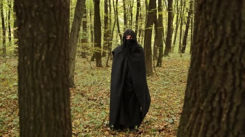 Figure Cloaked in Black Robe Standing in Forest
