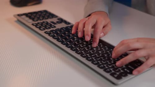 Girl focused on typing on a keyboard at a desk in a bright workspace