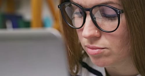 A Focused Woman in Glasses Looking at Laptop Screen with Using Internet