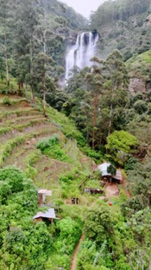 Quelques cabanes situées au pied des montagnes avec des jardins en terrasses sur la pente.