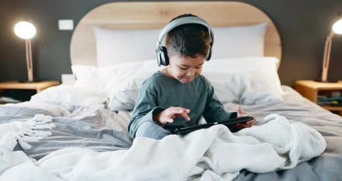Child Enjoying Tablet on Bed with Headphones