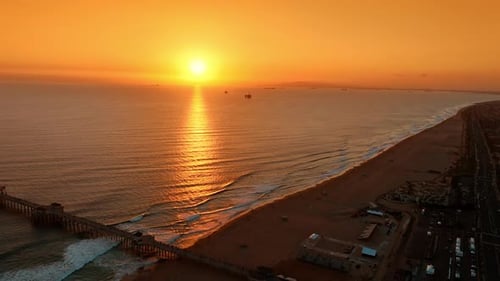 Setting sun lighting the coast with orange light. Footage at the beach of LA, California, the USA