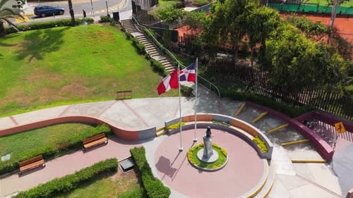 Vista aérea de un parque sereno en Lima, Perú, con una estatua y la bandera peruana