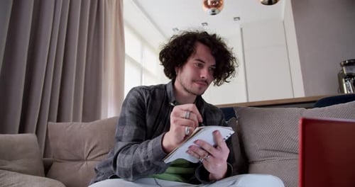 Young Adult Taking Notes While Working From Home
