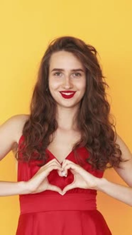 Woman in Red Dress Makes Heart Shape with Hands