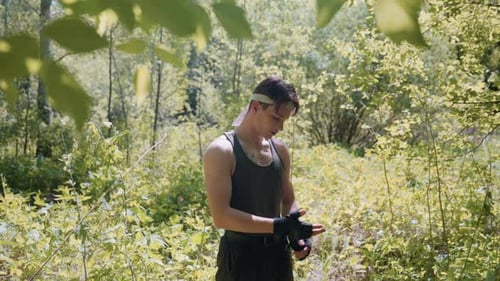 Adventurer Pulling Off Gloves In Sunlit Forest Clearing