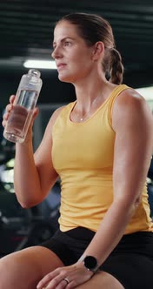 Woman, fitness and drinking with water for hydration, workout break or rest in health club