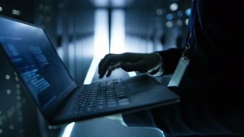 Especialista en TI que trabaja en una computadora portátil, es empleado de un gran centro de datos ultramoderno.