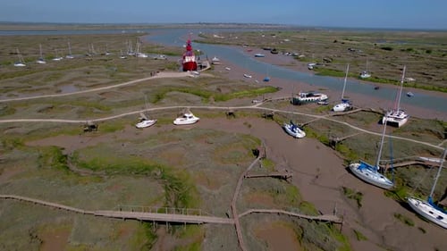 Aerial view over Essex marina towards Tollesbury lightship landmark boat docked on estuary marshland