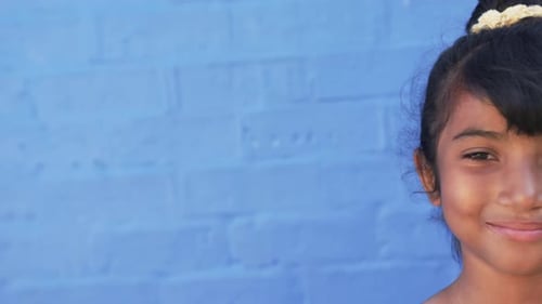 In a school setting, a young Hispanic student stands before a blue background with copy space