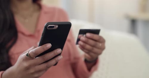 Woman Using Phone and Credit Card Indoors