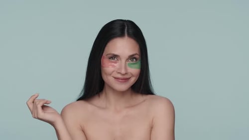 Portrait of a Seminude Woman with Various Hyaluronic Patches Under Her Eyes on a Blue Background
