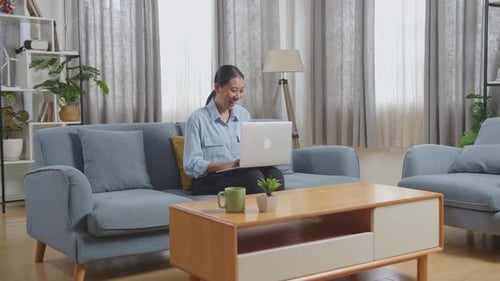 Woman Celebrates Success Using Laptop at Home