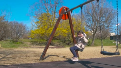 Swinging on metal swing against sky.