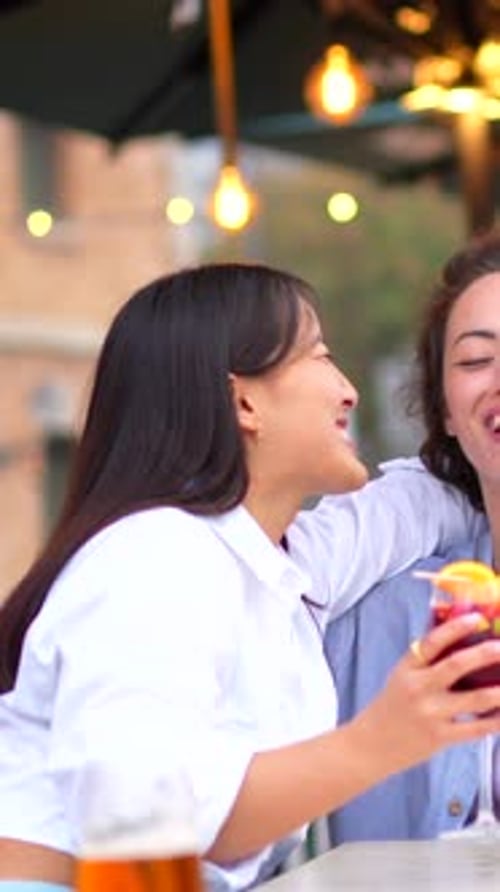 Friends Embracing While Drinking Cocktails in a Bar