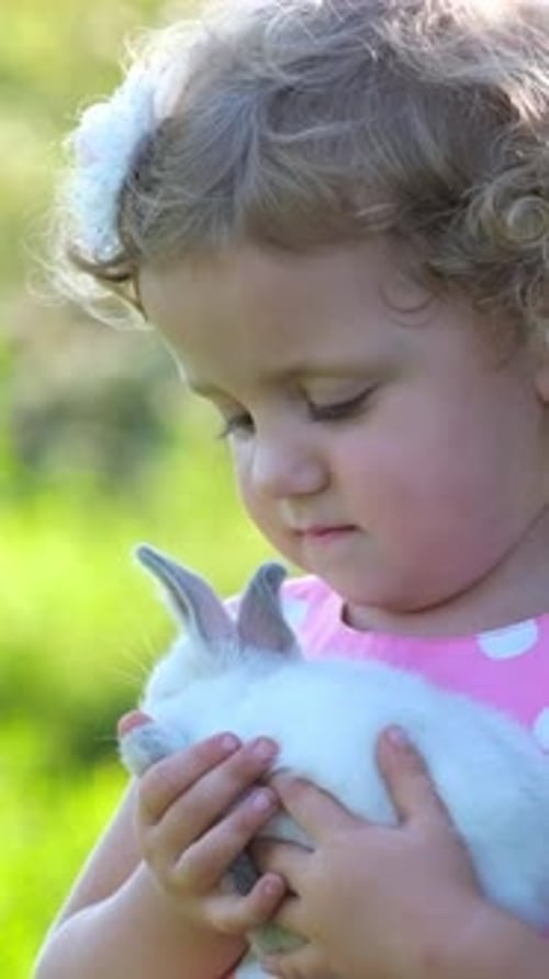 Girl Gently Holding a Small White Rabbit