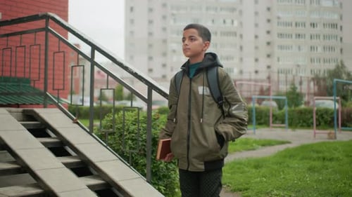 Teen Boy with Book Walking into Apartment Building