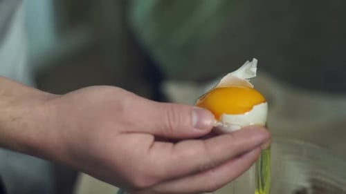 Hands cracking and separating an egg yolk