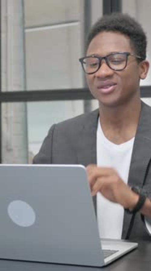 Smiling Man Video Conference on Laptop in Office