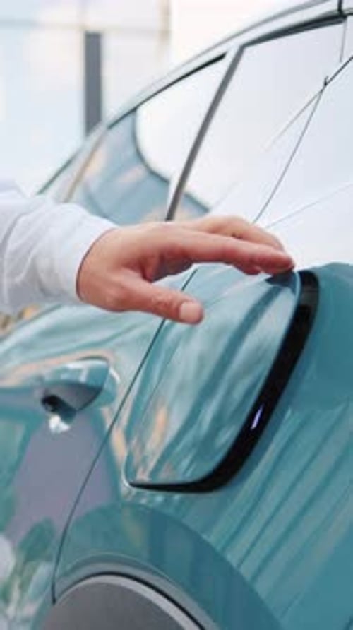 Nahaufnahme männlicher Hände, die ein Elektroauto-Ladegerät an ein entladenes Fahrzeug anschließen und das starten