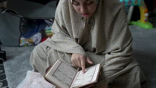 Young Muslim Woman Reading Quran At Home - Close Up