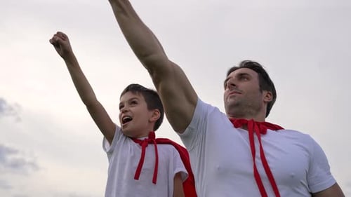 Father and Son Wearing Capes Look into Distance