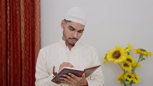 Young Adult Writes in Book Indoors