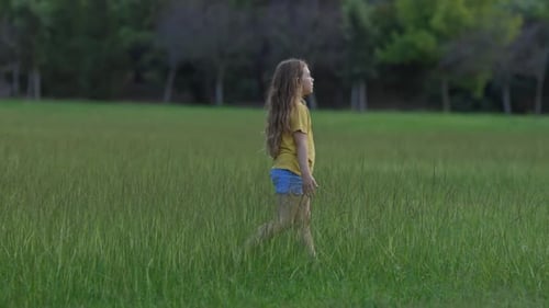 Young Girl Joyfully Walking Through a Sunlit Field of Tall Grass