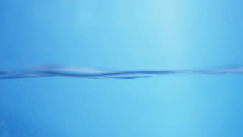 Water droplets fall from above, creating smooth circular ripples on the surface, representing purity