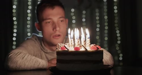 A Young Man Blows Out Candles on a Birthday Cake Alone