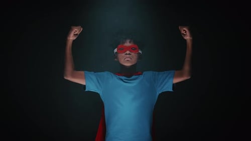 Studio Portrait of Little Boy in Superhero Suit Showing Biceps on Camera