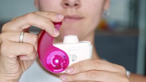 Vue rapprochée d'une femme utilisant un inhalateur à poudre sèche pour le traitement de l'asthme ou de la BPCO