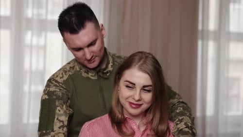 Military Man Embraces and Kisses Smiling Woman