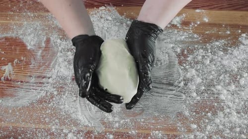 Hands Kneading Dough on Flour Covered Wood Board