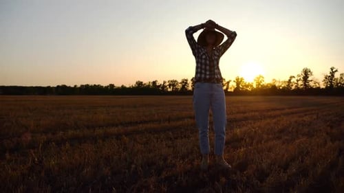 Adult Agronomist in Straw Hat Exploring Barley on Meadow at Sunset Female Farmer Examining Ripe