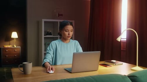 Woman Works at Laptop in Warmly Lit Room
