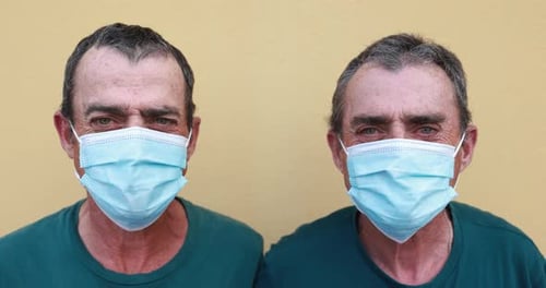 Two men wearing masks against a yellow background