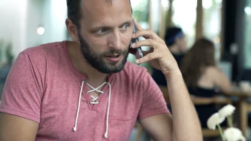 Young man enjoys lunch and conversation on his cellphone at a cafe