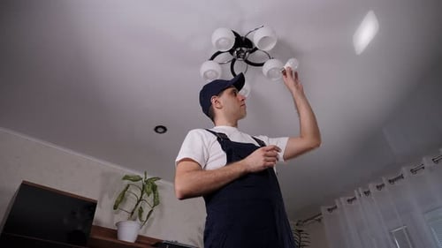 Young Adult Installing Lightbulb in Ceiling Fixture
