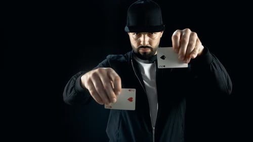 Professional Street Magician in a Cap Performs Impressive Sleight of Hand Card Trick. Background is