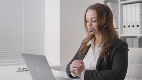 Businesswoman with Headset Talking Online at Desk