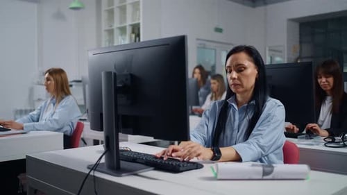 Brunette Woman And Her Female Colleagues Working With Computers In Modern Office Portrait